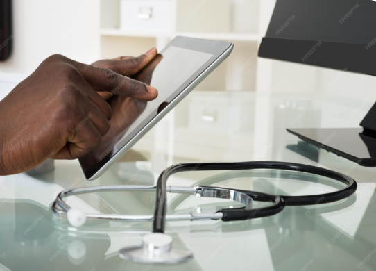 main d'un medecin tenant une tablette avec aupres de lui stéthoscope.